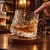 Palec popycha obrotową szklankę do whisky, trunek wiruje, szklanka przechyla się na podstawce